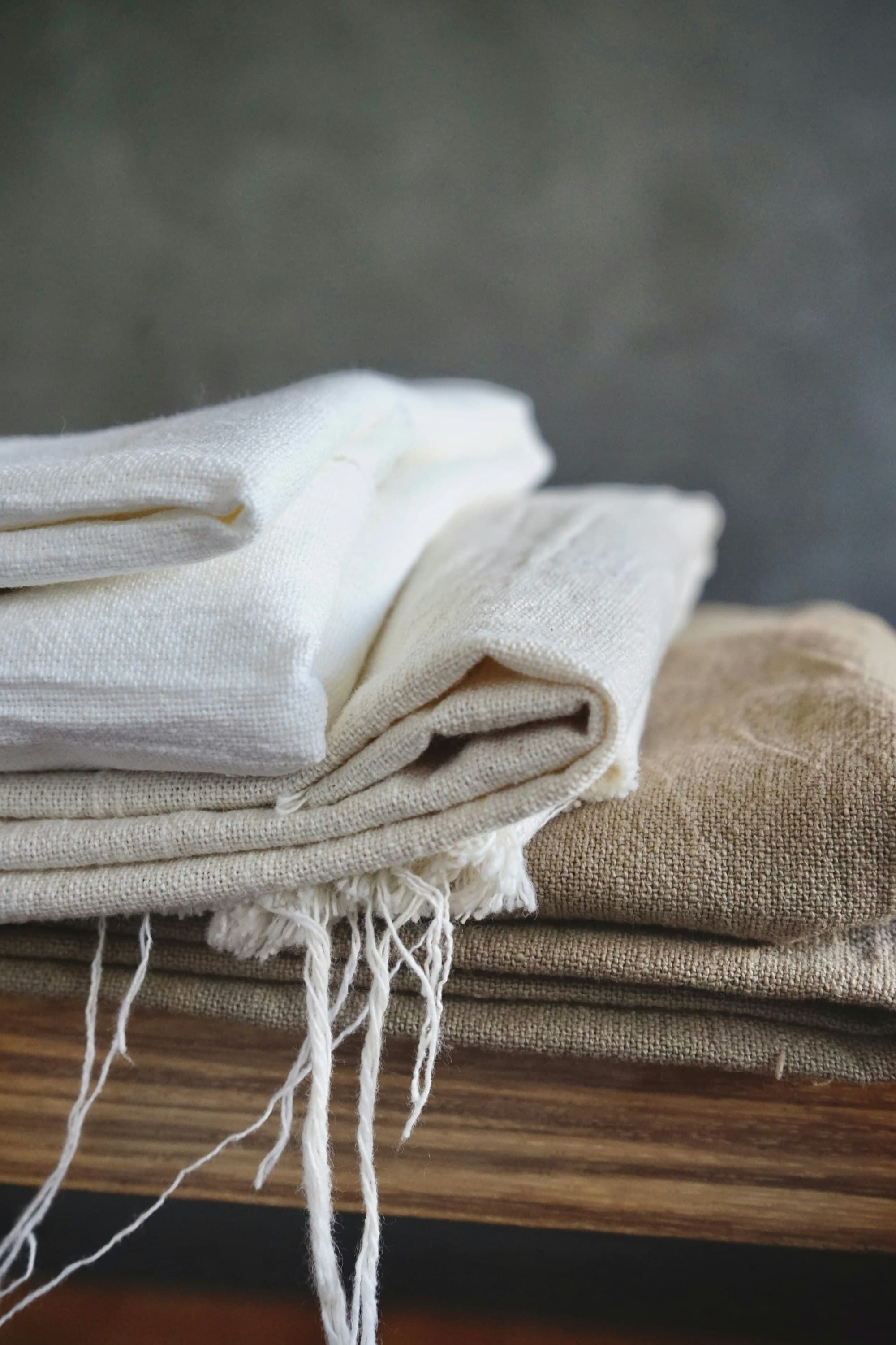 Folded stacks of natural and beige linen cloth with frayed edges