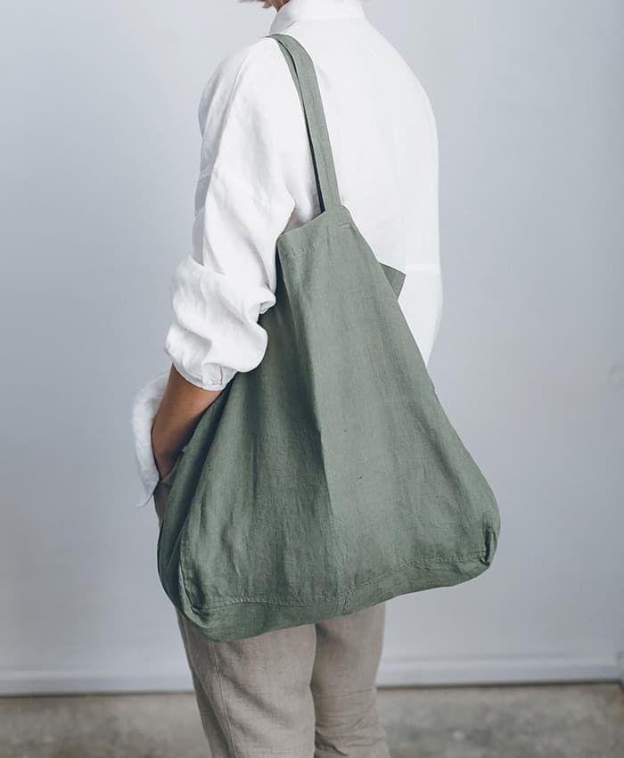 Model carrying a sage linen tote bag