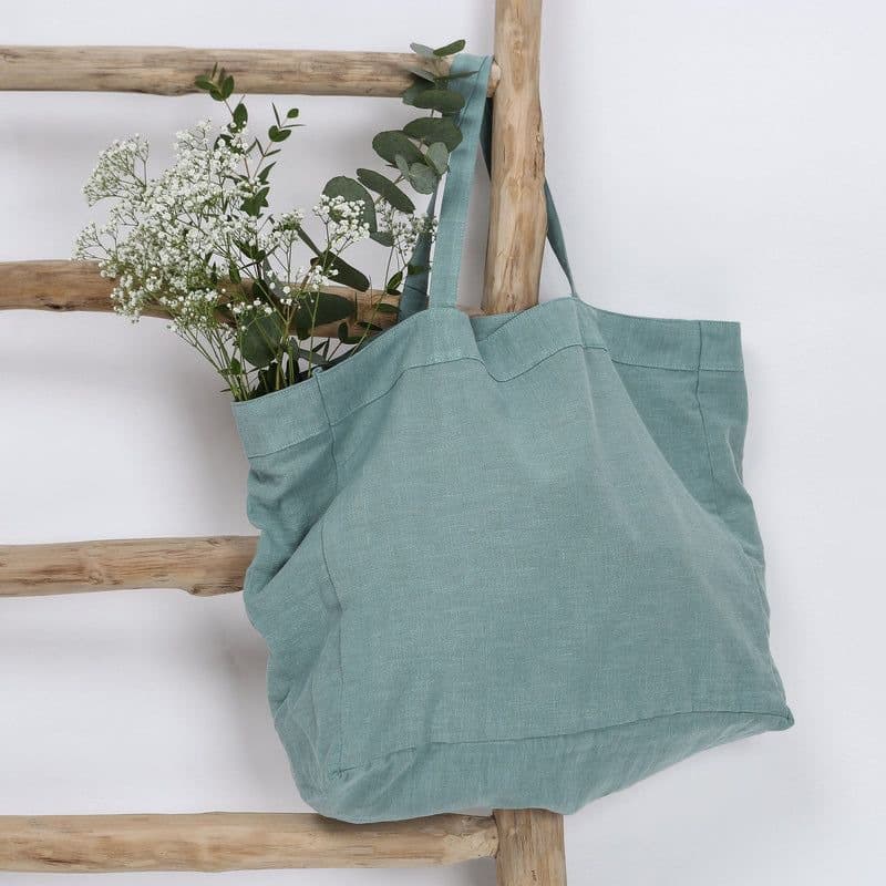 Teal linen tote hanging on a wooden ladder with dried flowers