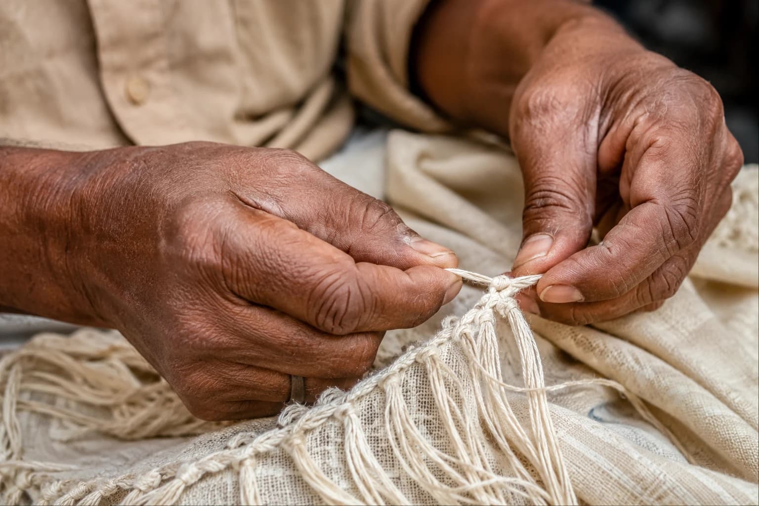 Artisan's hands finishing the fringe of a woven scarf