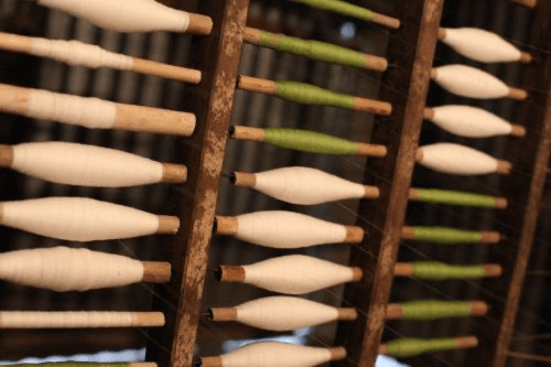 Thread bobbins on wooden spindles in a textile workshop