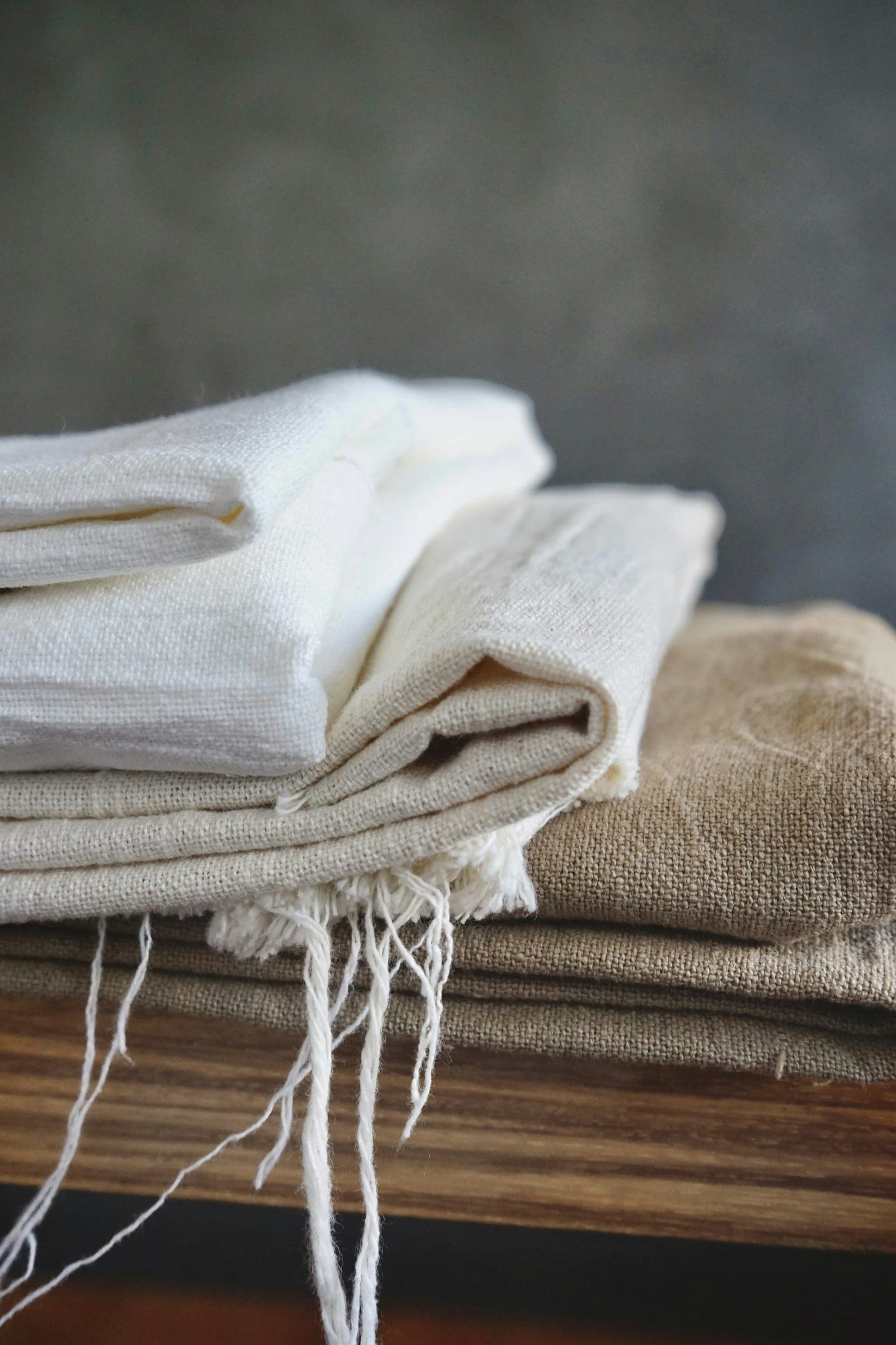 Folded stacks of natural and beige linen cloth with frayed edges